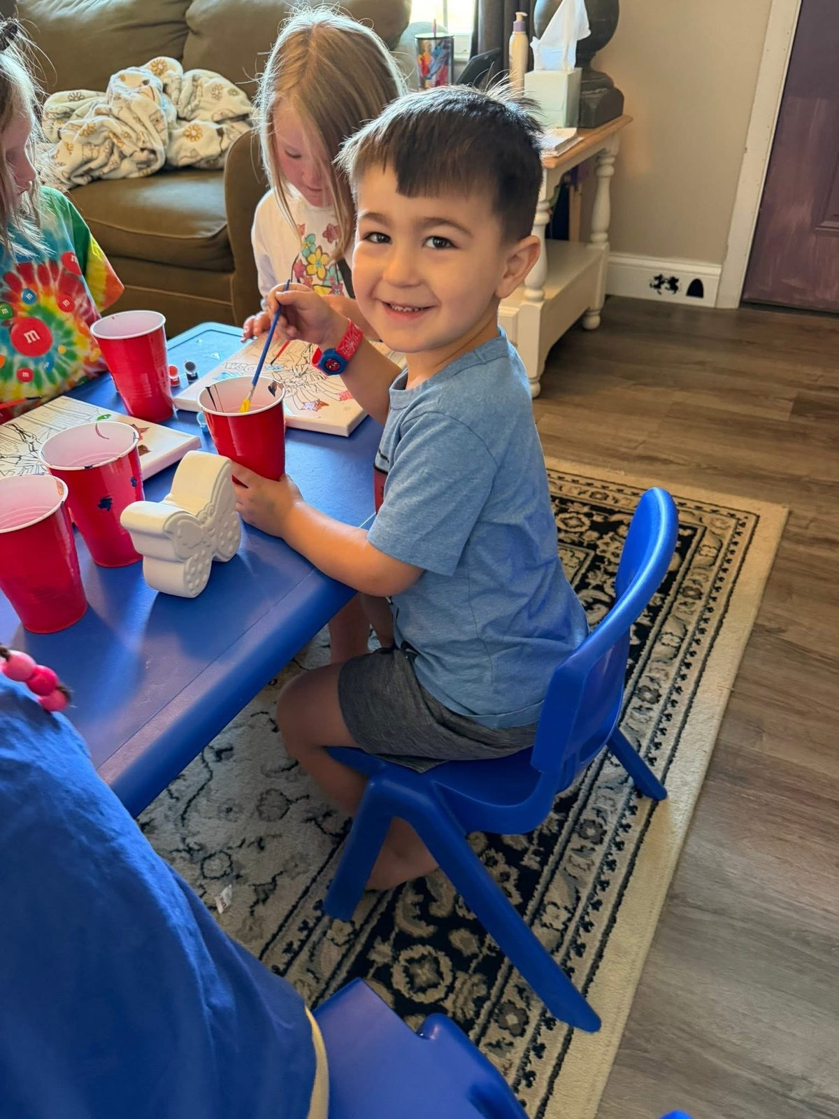 Young boy sitting at a blue table eating snacks at Mother Goose Day Care